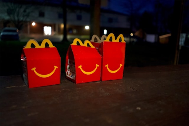 Three McDonald's Happy Meal boxes on a table outdoors at night.