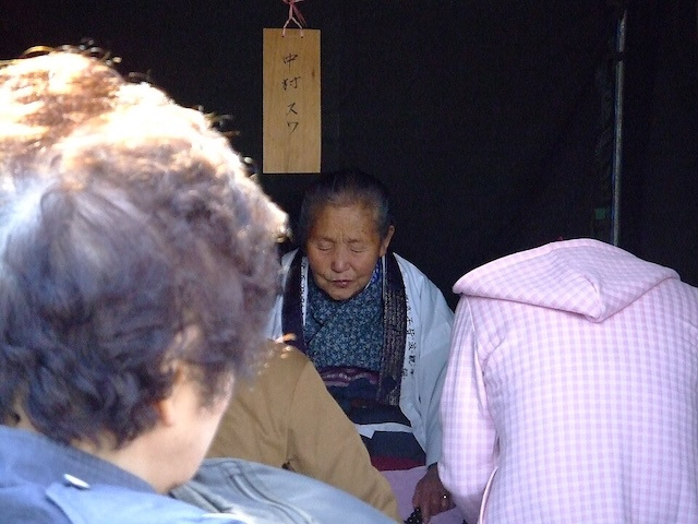 An itako sits in front of a group of spectators.