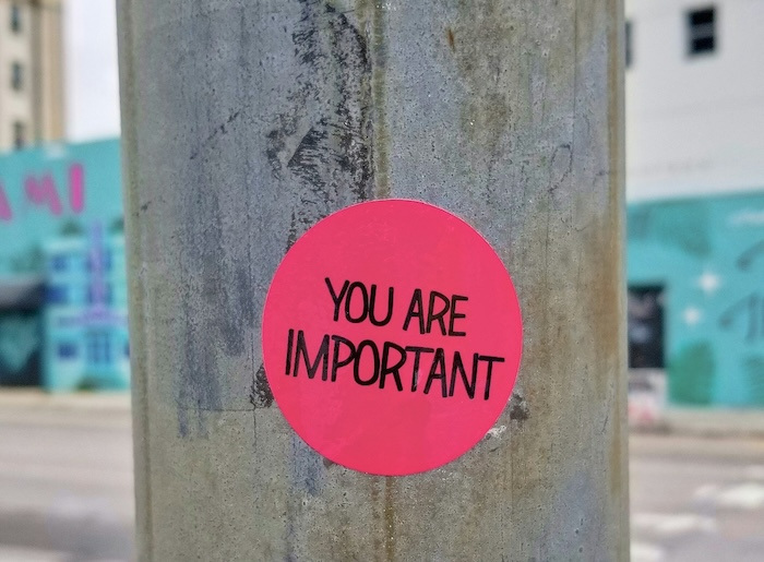 A pink sticker on a streetpole that reads, "You are important."